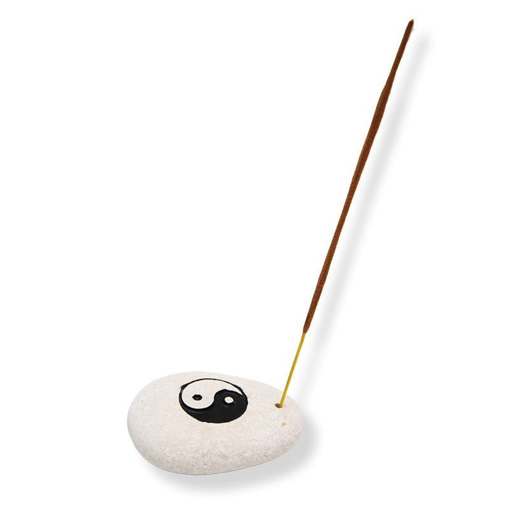 Stone incense holder with yin yang carved into top and painted and small hold drilled to one side to hold an incense stick - zoomed out view